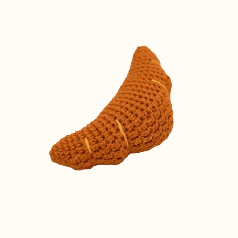Handmade crochet croissant in brown yarn showcasing DIY crochet croissant pattern by The Knit Krazy
