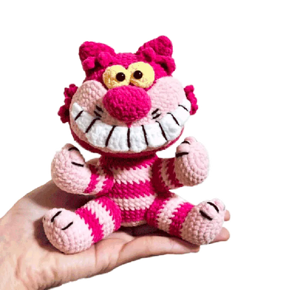 Hand holding a colorful crocheted Cheshire Cat toy made using a free crochet cheshire cat pattern