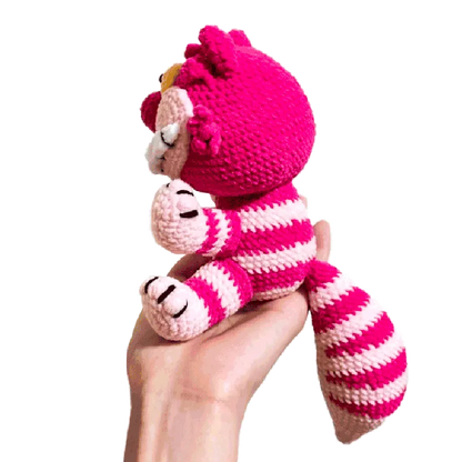 Hand holding a pink and white striped crocheted Cheshire cat toy from free crochet cheshire cat pattern