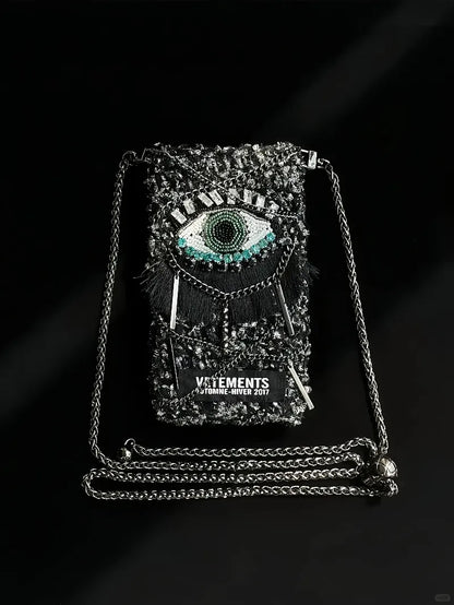 FREE｜cyberpunk crochet phone bag pattern featuring a black bag with a detailed eye design and metal chain strap
