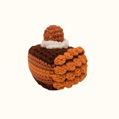 Handcrafted crochet chocolate cake pattern with layered brown and tan yarn and a dollop of cream on top