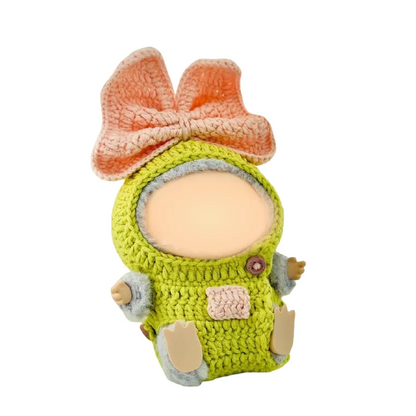 Crochet doll outfit pattern featuring a green outfit with a large peach bow on the head