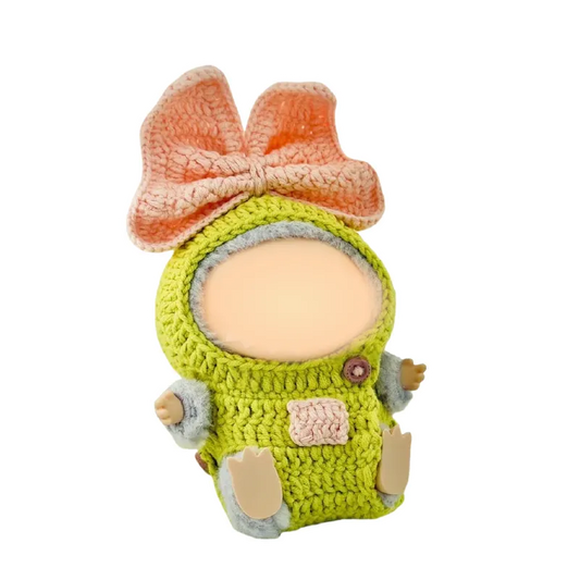 Crochet doll outfit pattern featuring a green outfit with a large peach bow on the head