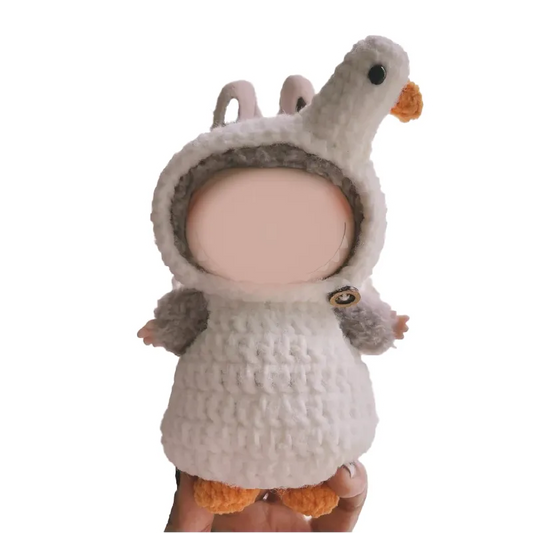 Hand holding a baby doll wearing a white crochet goose outfit pattern with orange beak and feet