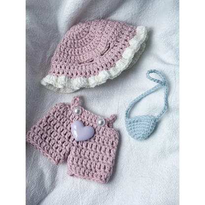 Pink knit doll outfit with a hat, shorts with heart decoration, and a small blue purse