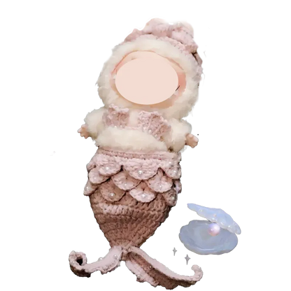 Handmade mermaid crochet doll with pink and white yarn details and a pearl inside a shell nearby mermaid crochet doll pattern
