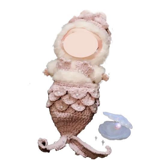 Handmade mermaid crochet doll with pink and white yarn details and a pearl inside a shell nearby mermaid crochet doll pattern