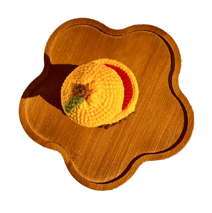 Handmade crochet capybara storage box pattern in yellow displayed on a wooden tray